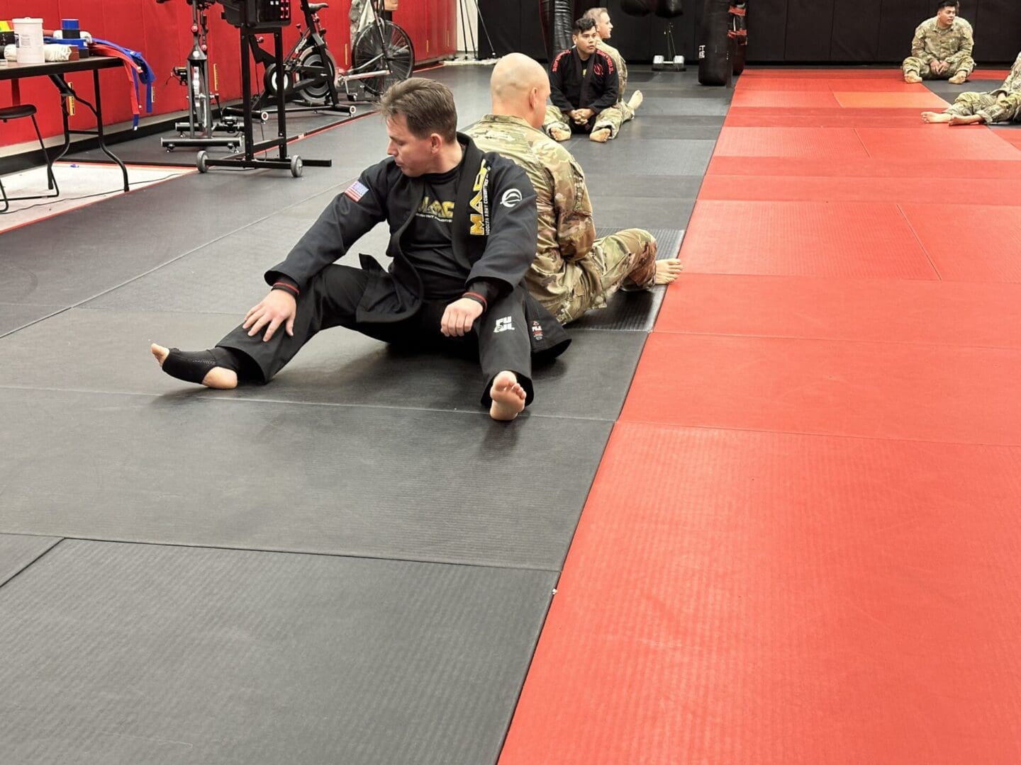 A man and woman sitting on the ground in a gym.