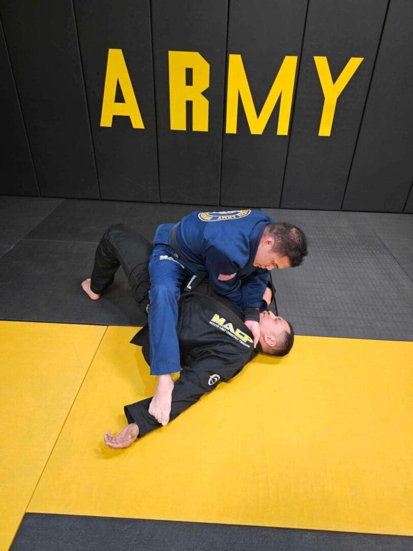 Two men are wrestling on a yellow and black mat.