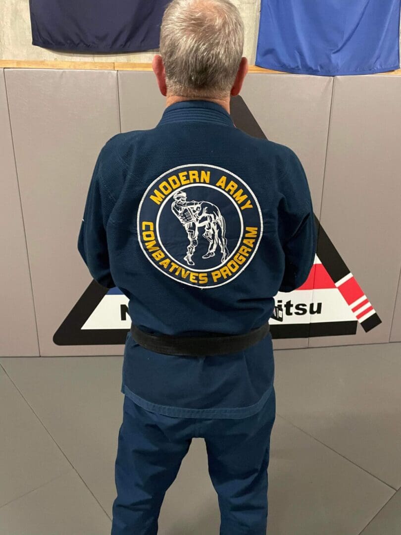 A man in blue jacket standing next to wall.