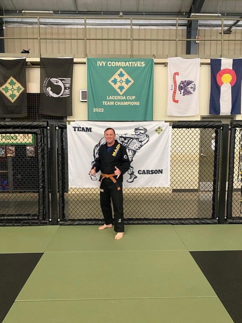 A man standing in front of flags and a fence.